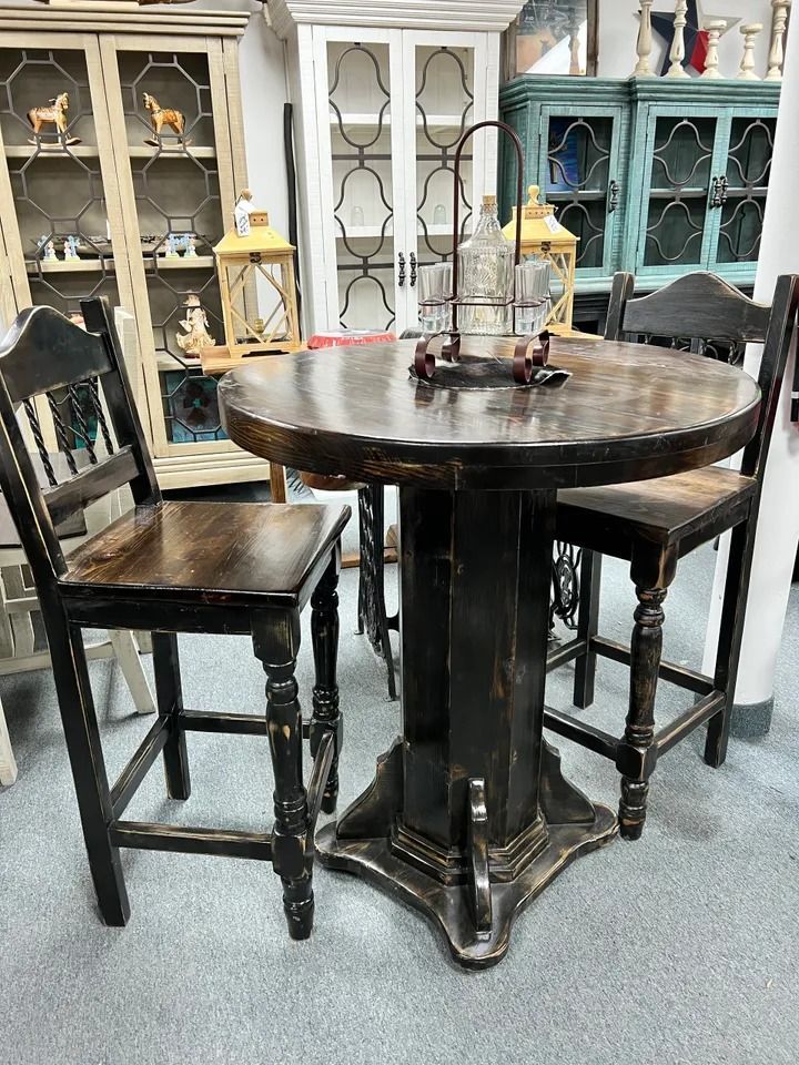 A round, dark wood table with two matching chairs, set in a shop.