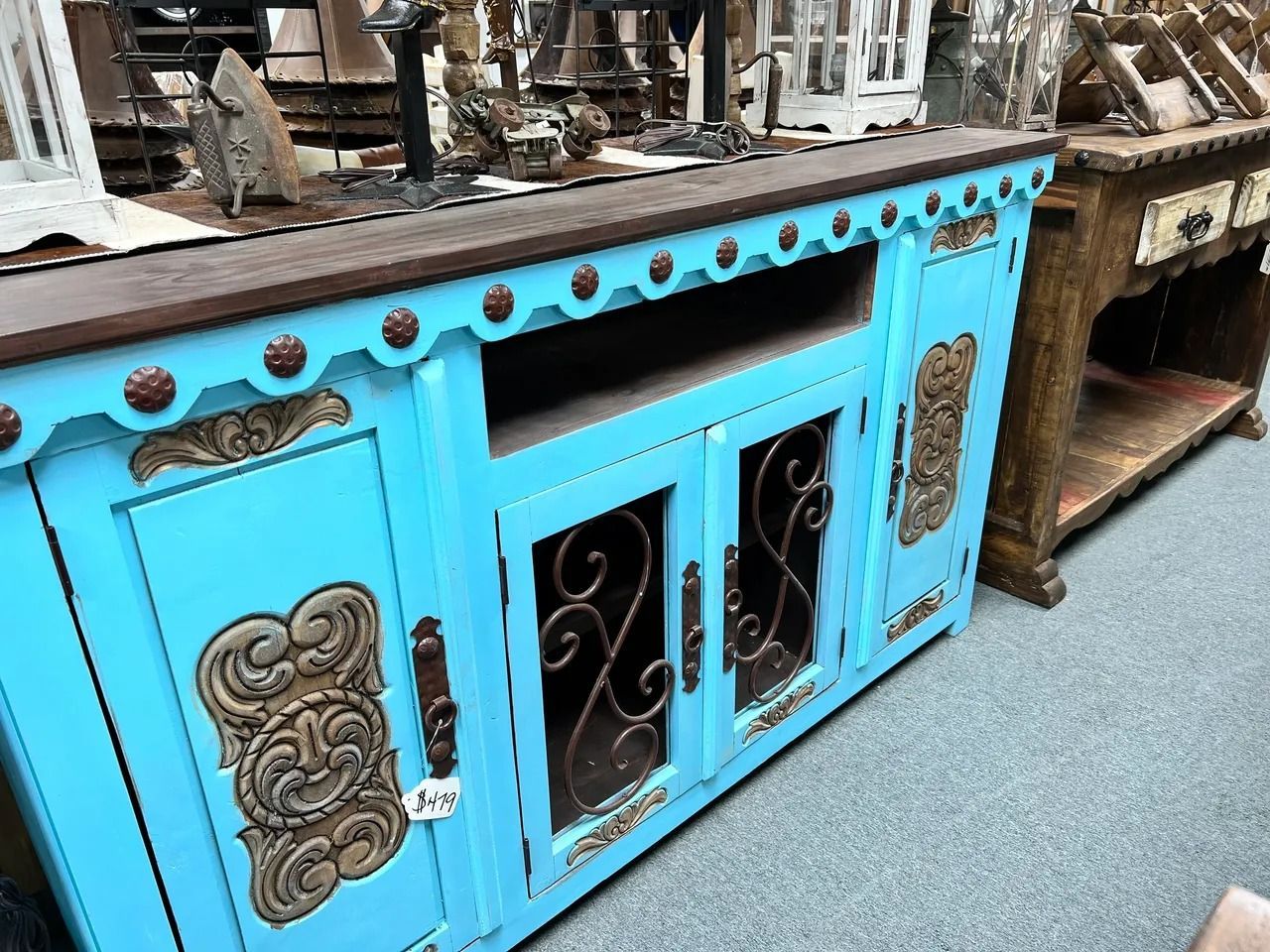 Turquoise cabinet with brown top and iron scrollwork.