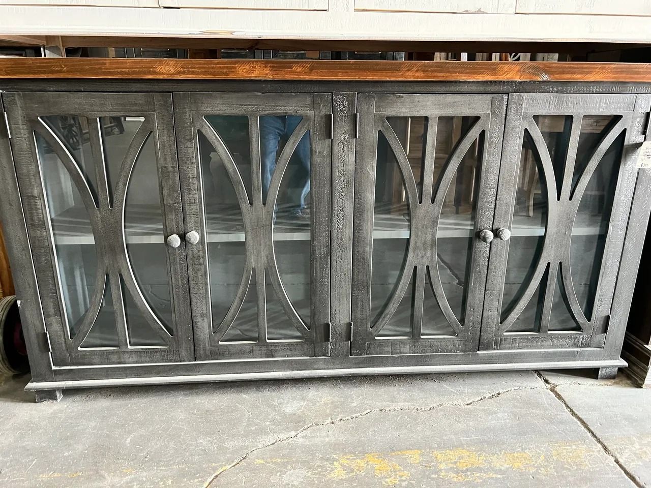 Metal and glass cabinet with wood top. Gray metal frame with decorative arched design.