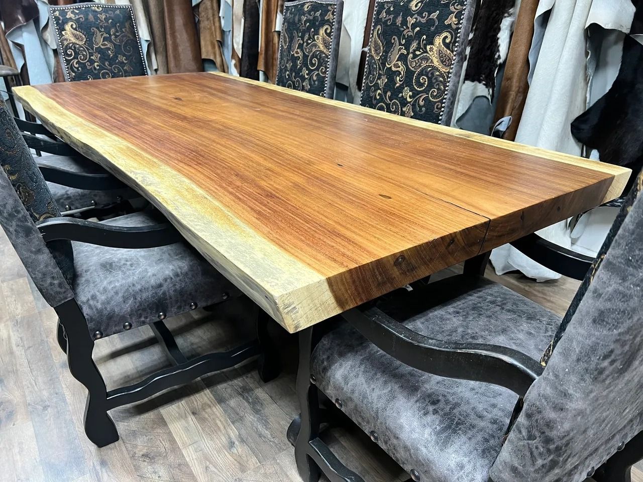 Wooden dining table with live edge, surrounded by cowhide chairs.