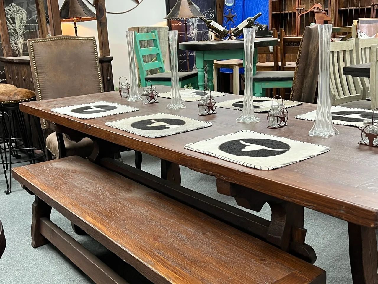 Wooden dining table with bench, set for six, tall vases, in furniture store.