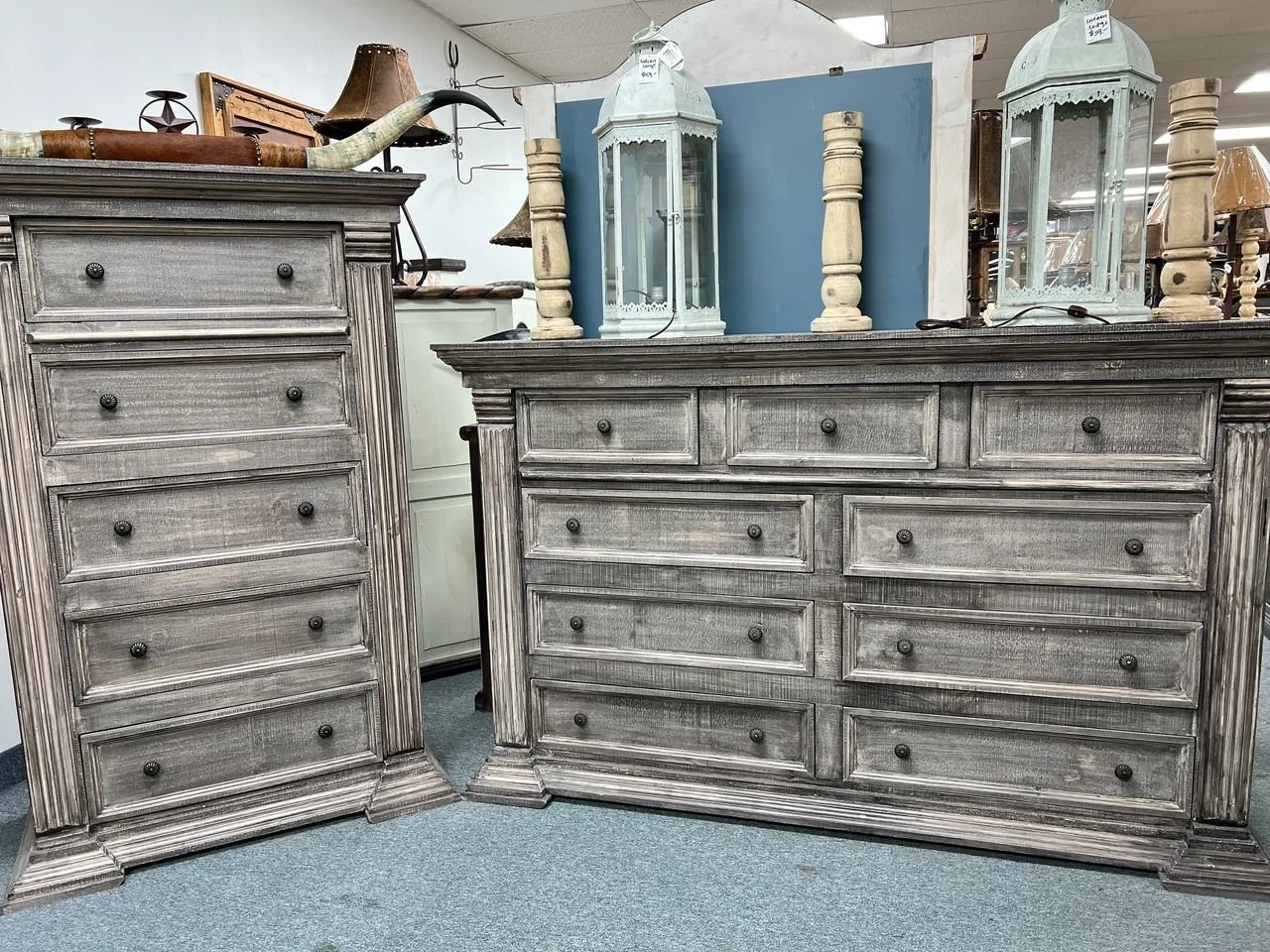 Two weathered gray wooden dressers with lanterns and candles on top.