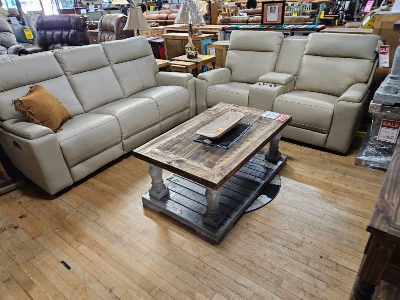 Beige leather sofa, recliner, and wooden coffee table in a furniture store.