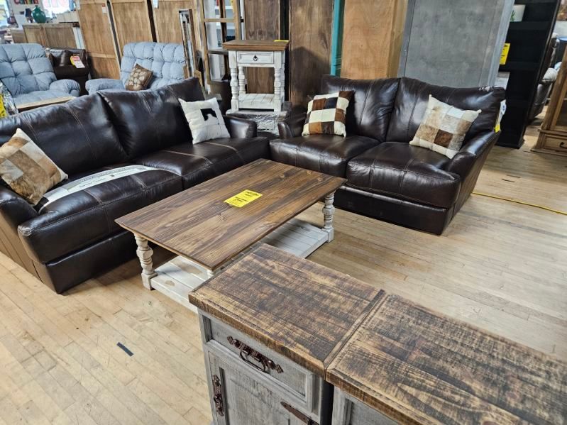 Leather sectional, wooden coffee table, and side table in a furniture store.
