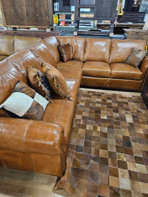 Brown leather sectional sofa with decorative pillows on a patterned brown rug.
