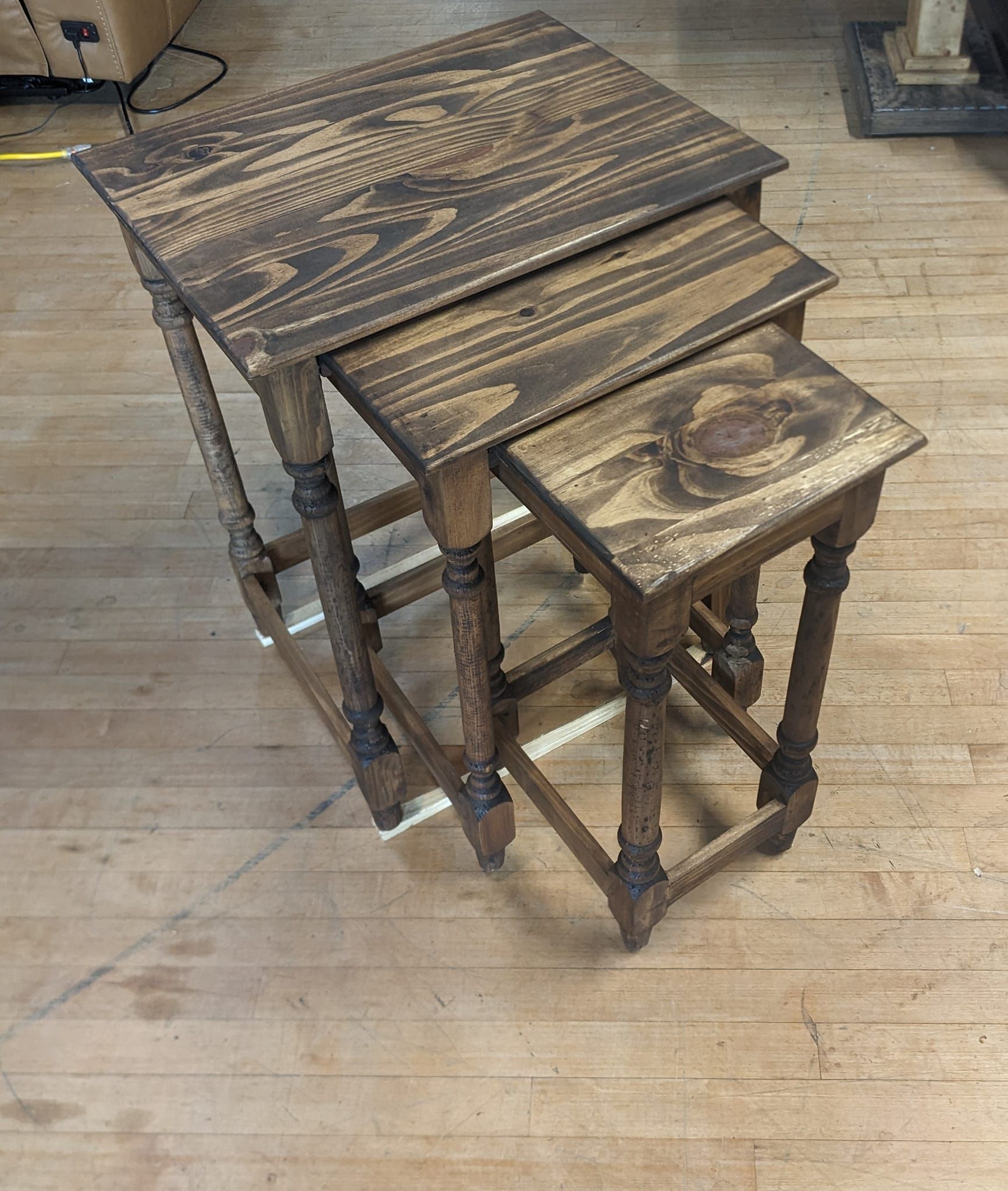 Nesting tables of varying sizes in a brown stained wood on a wooden floor.
