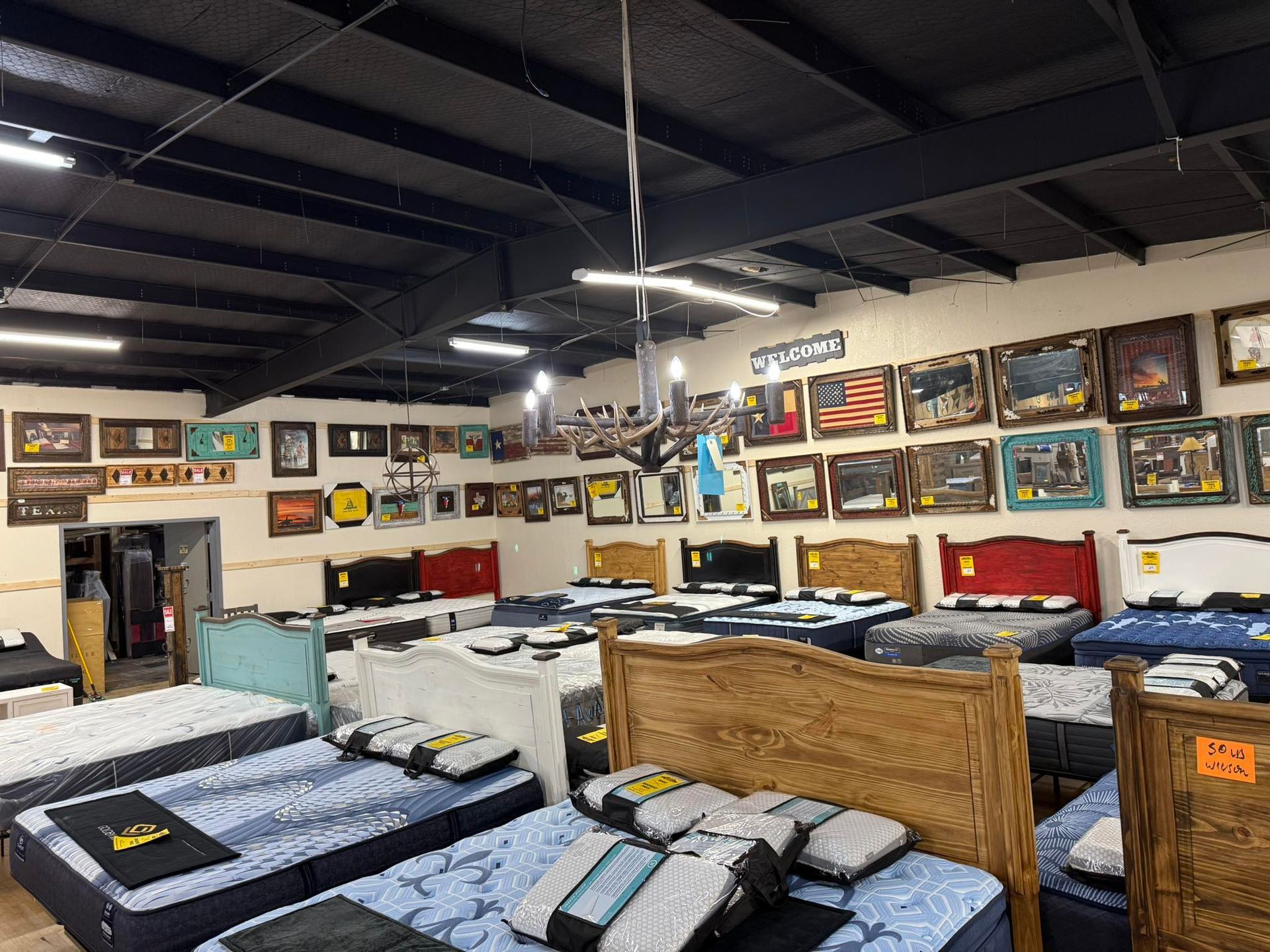 Mattresses displayed in a store with framed artwork on the walls.