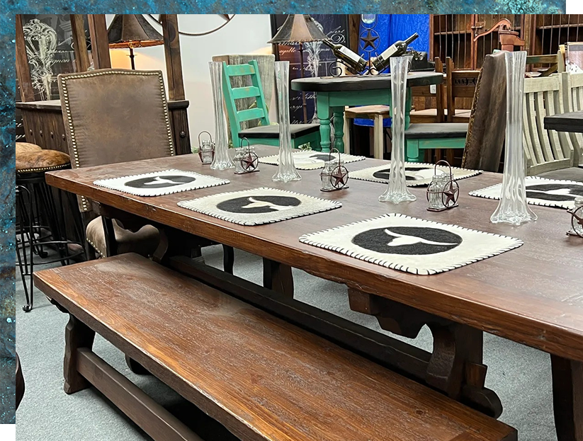 Wooden dining table with bench and chairs.  Set with placemats, vases, and candle holders. Rustic interior.