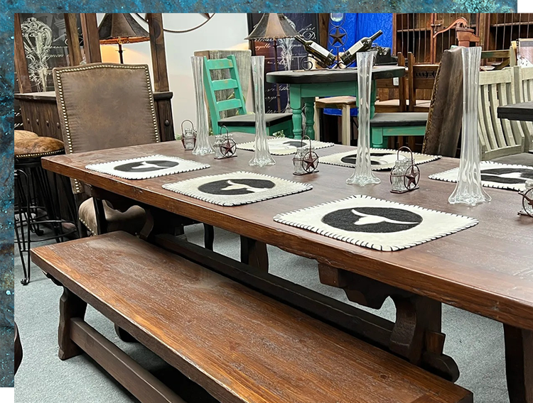 Wooden dining table with bench and chairs.  Set with placemats, vases, and candle holders. Rustic interior.