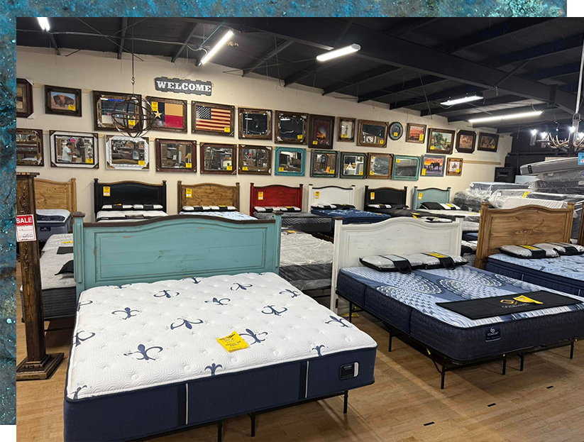 Inside a furniture store, mattresses on display. Several beds are set up with colorful headboards and wood flooring.