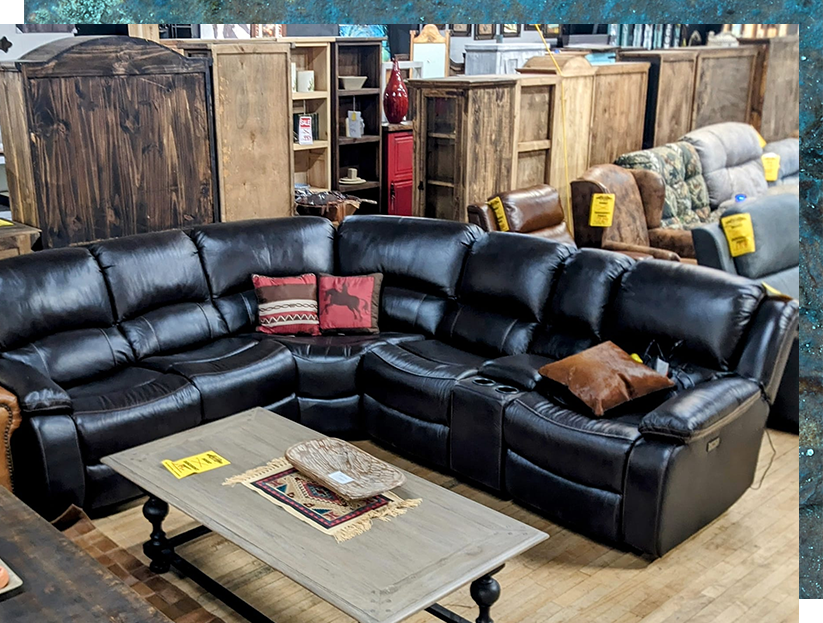 Black leather sectional sofa in a furniture store, with a coffee table in front.