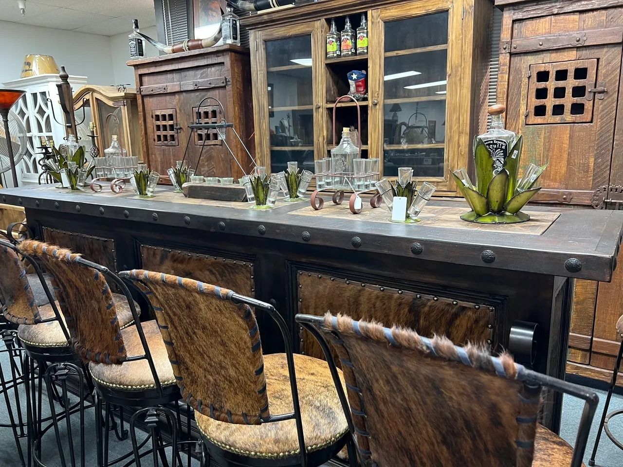 Bar with rustic decor, cowhide bar stools, and wooden cabinets.