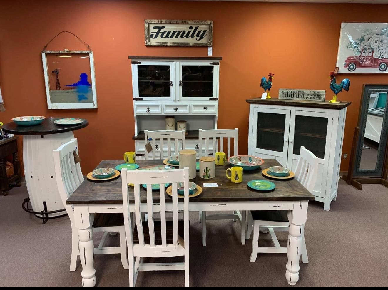 Dining room set with distressed white table and chairs, hutch, and bar table. Orange wall.