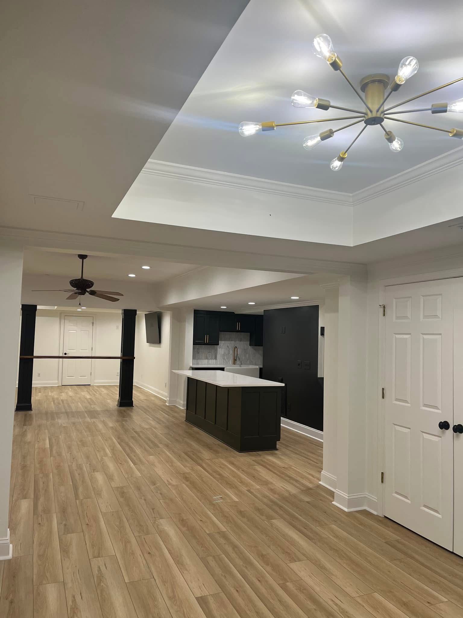 Modern kitchen with island, cabinets, and a unique light fixture.  Neutral colors, wood-look flooring.