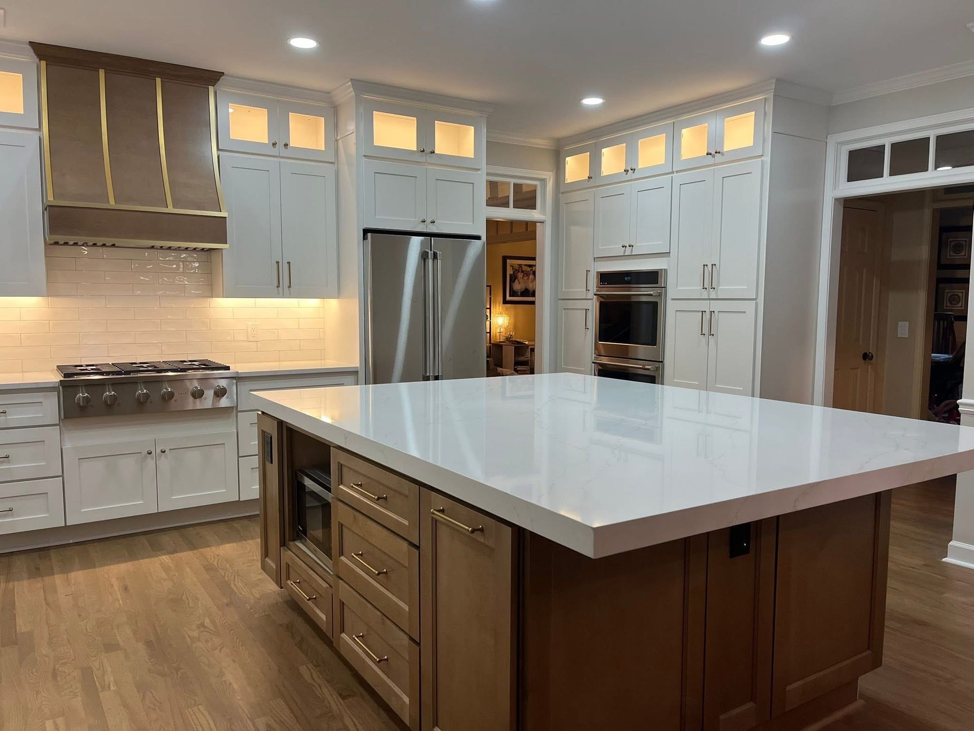 A modern kitchen with white cabinets, stainless steel appliances, and a large island with a quartz countertop.