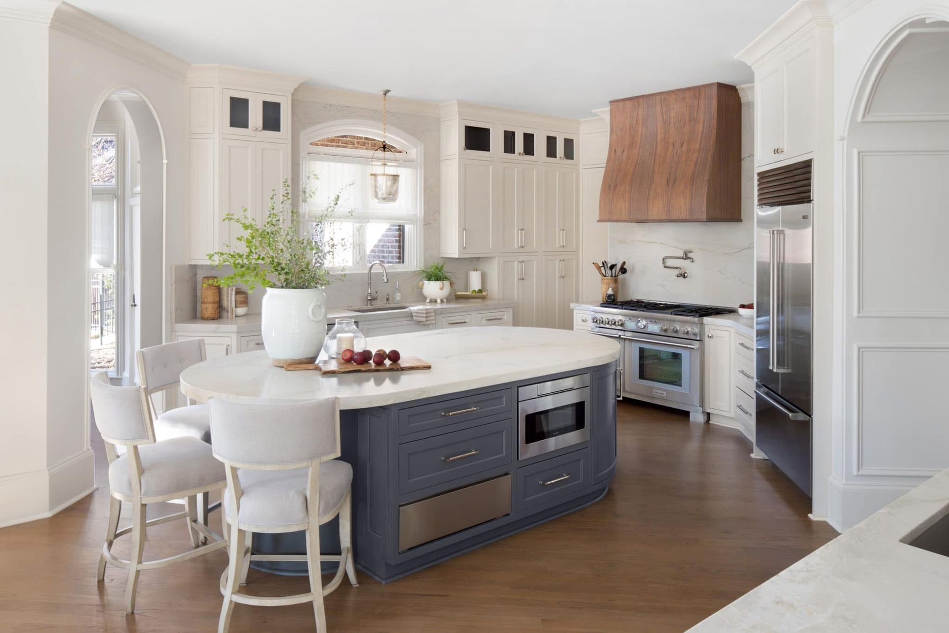 Elegant kitchen with a blue island, white cabinets, and a wooden range hood.