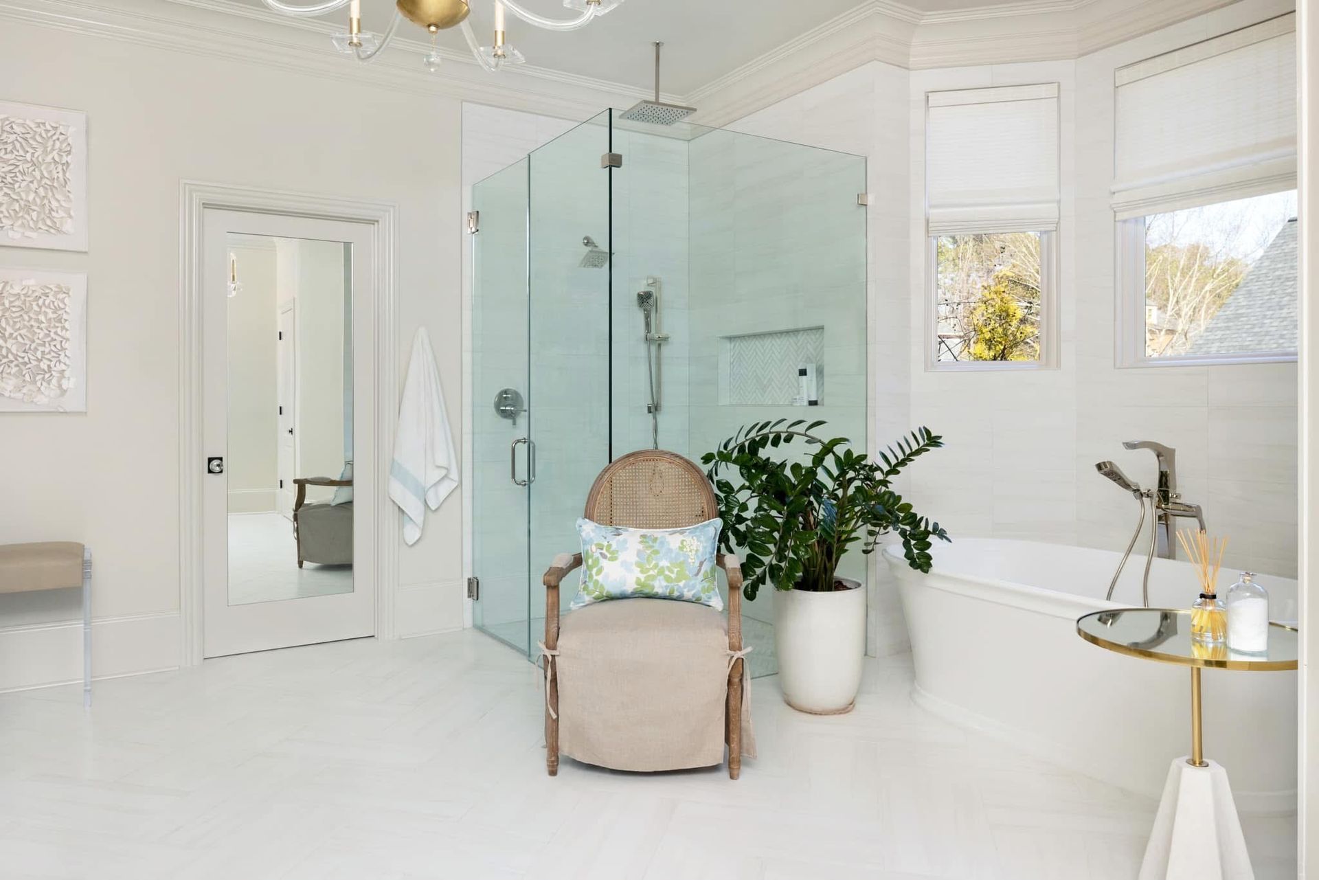 White bathroom with a glass shower, soaking tub, and chair.