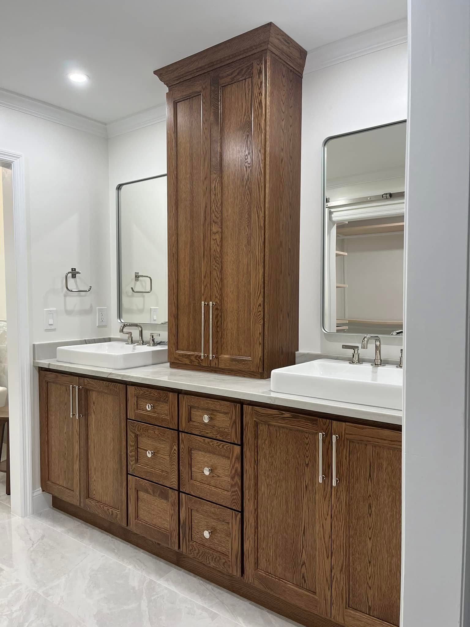 Bathroom vanity with wood cabinets, center storage, two sinks, and mirrors.