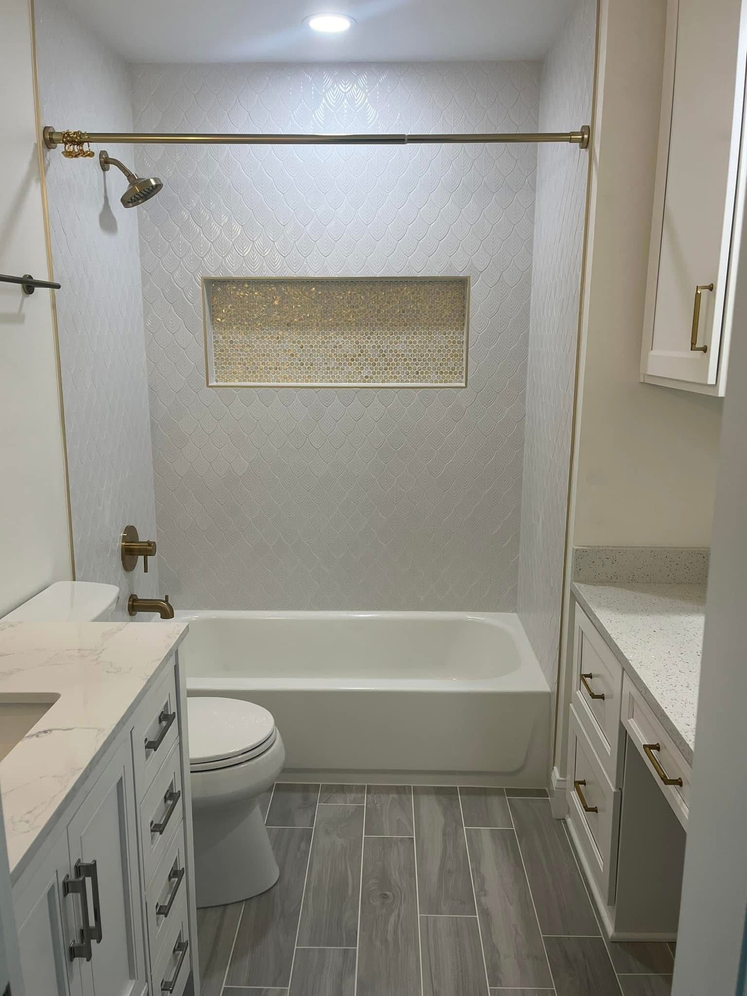 Bathroom with white mosaic-tiled shower, vanity, toilet, and light-colored wood-look floor.