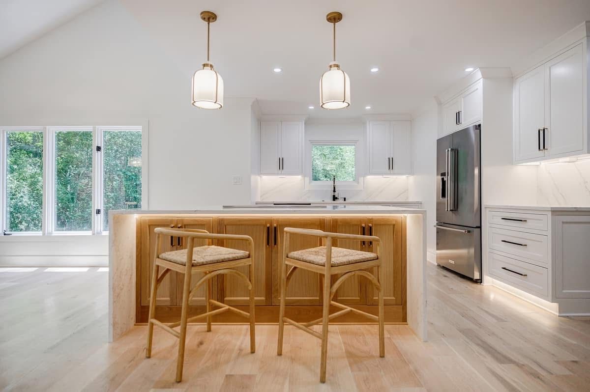 Modern kitchen with light wood island, two bar stools, and white cabinets.