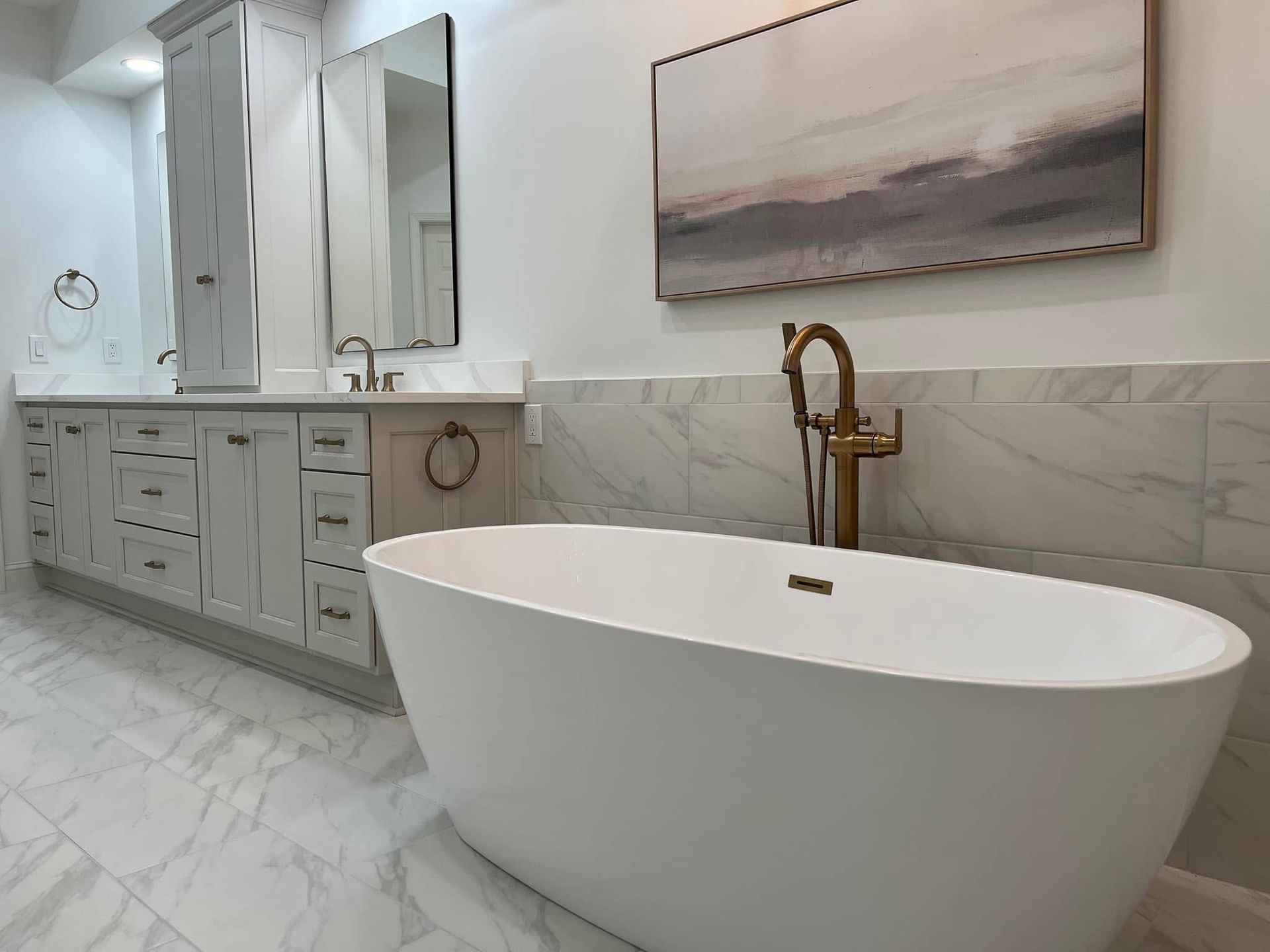 Modern bathroom with a white oval bathtub, vanity, and marble tile flooring.