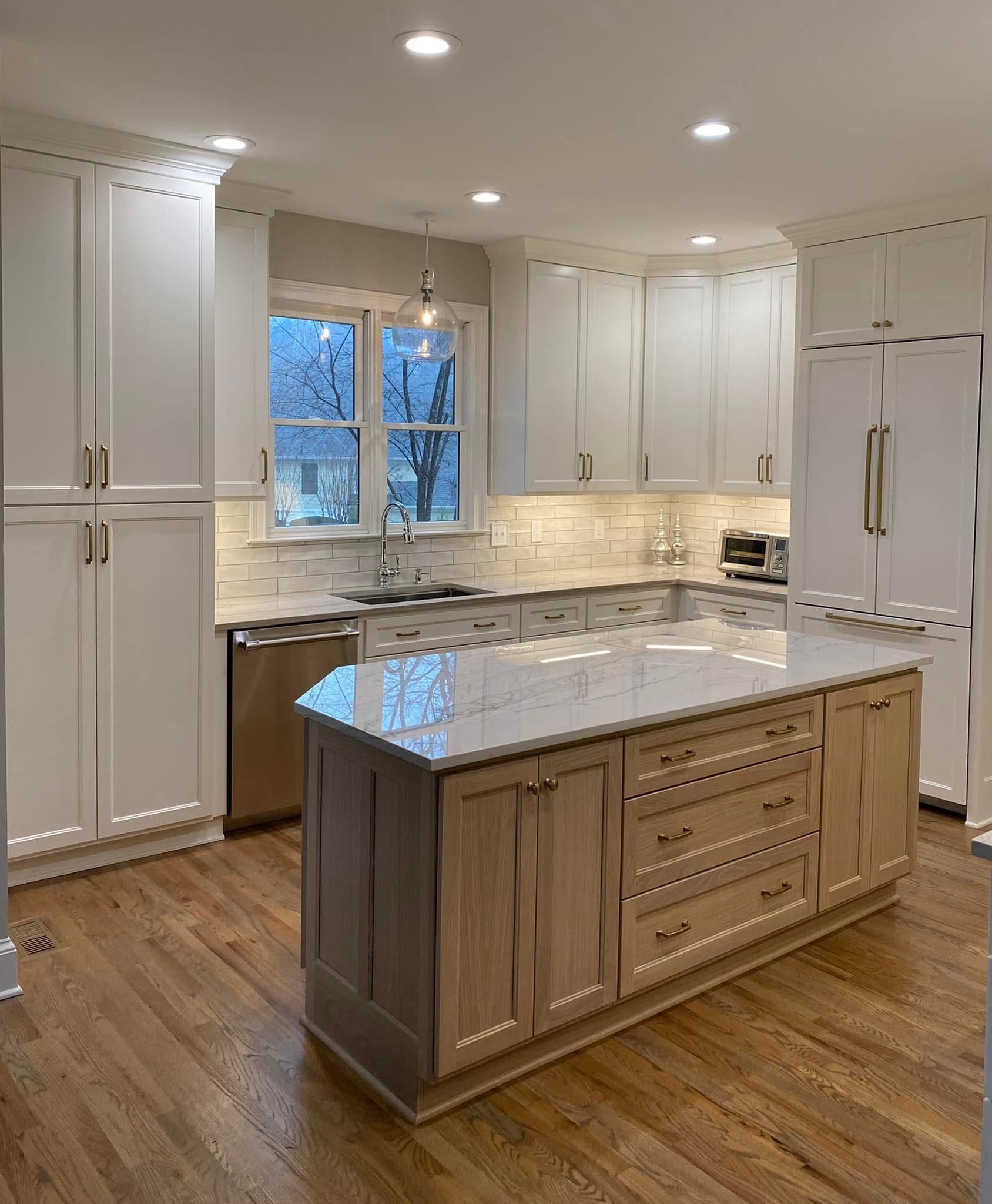 Kitchen with white cabinets, light wood island, stainless steel appliances, and hardwood floors.
