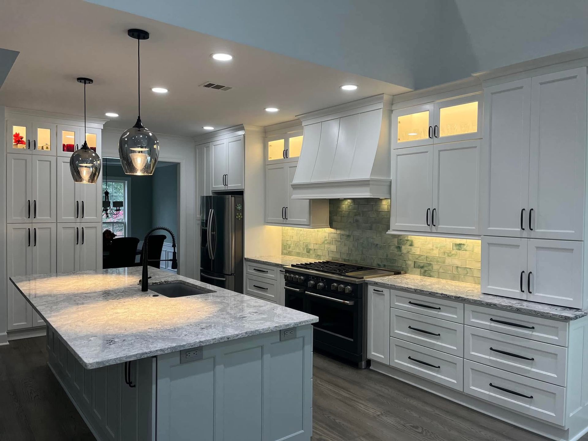 White kitchen with island, cabinets, countertops, and black appliances.