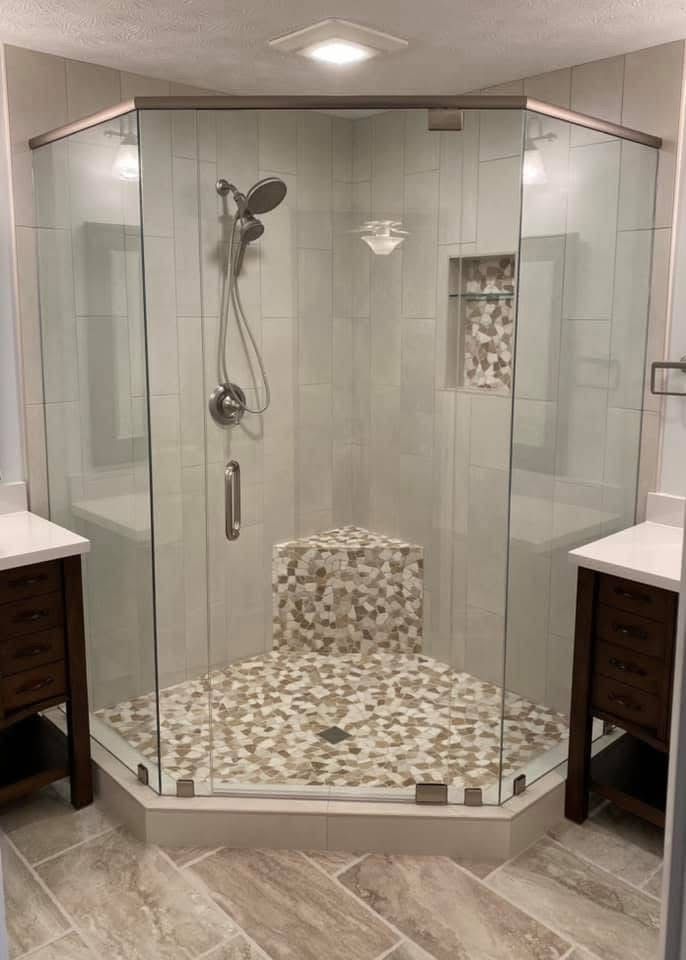 Modern shower with glass doors, tiled walls and floor, built-in bench, and a niche for toiletries.