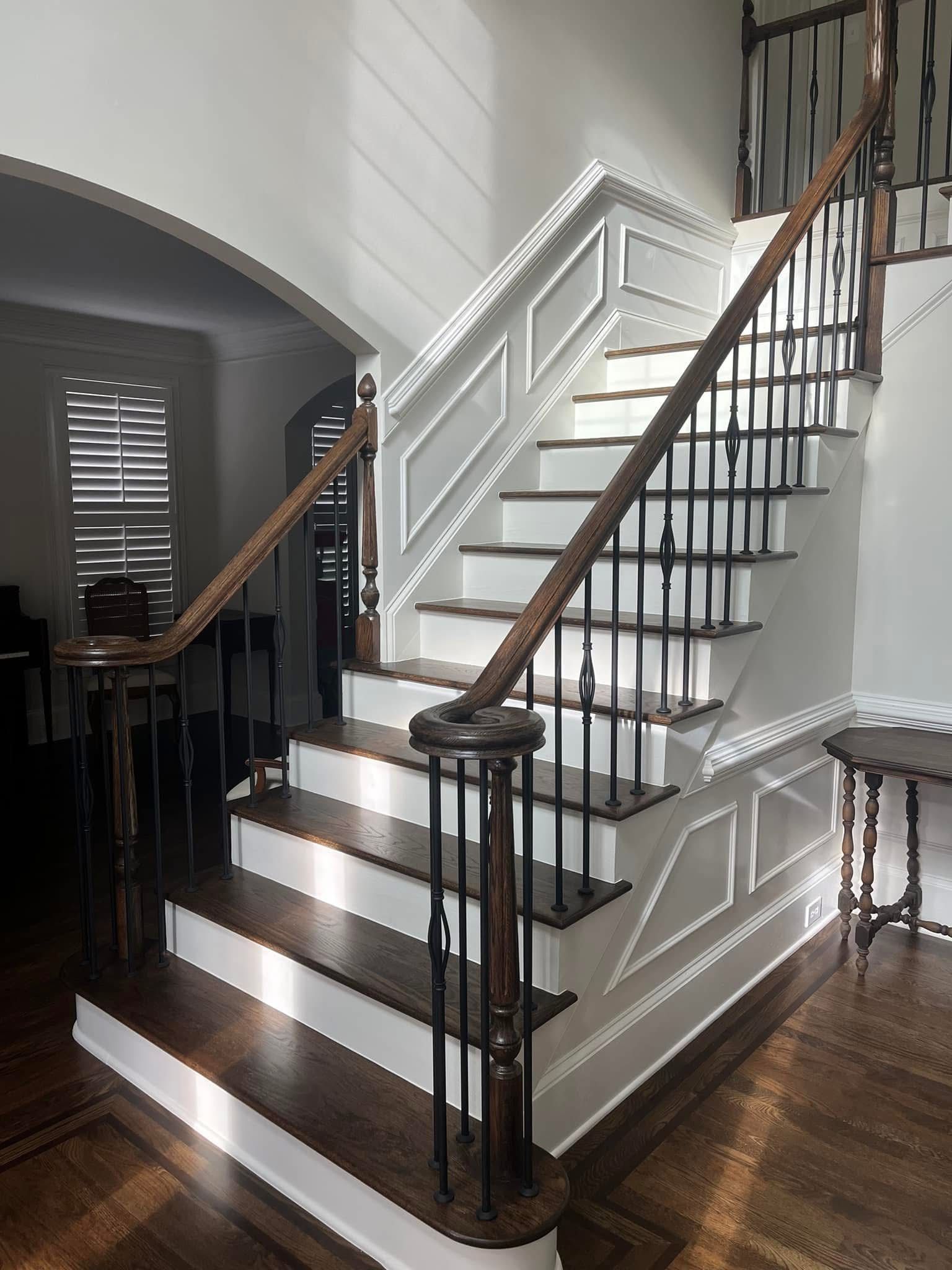 Wooden staircase with dark brown treads and white risers, black spindles.