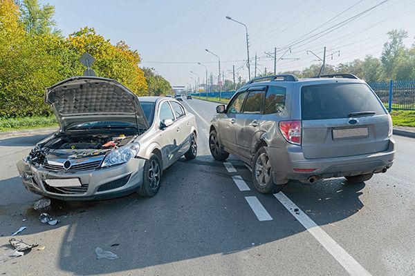 Two cars are involved in a car accident on the side of the road.