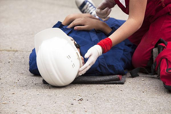 A person is laying on the ground with a hard hat on their head.