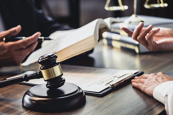 A judge 's gavel is sitting on a wooden table next to a clipboard.