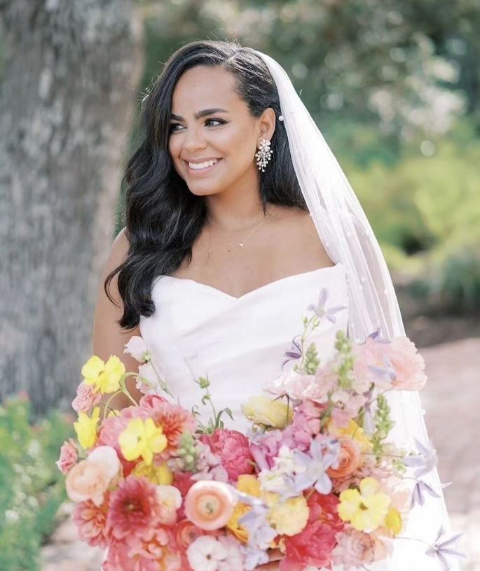 The bride is wearing a veil and holding a bouquet