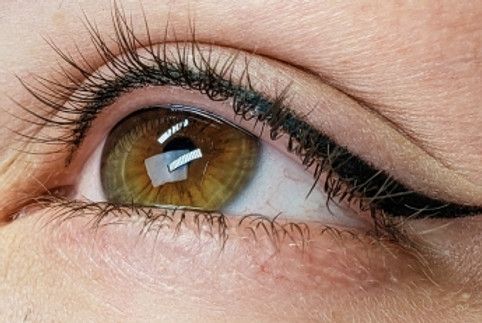 A close up of a woman 's eye with long eyelashes and eyeliner.
