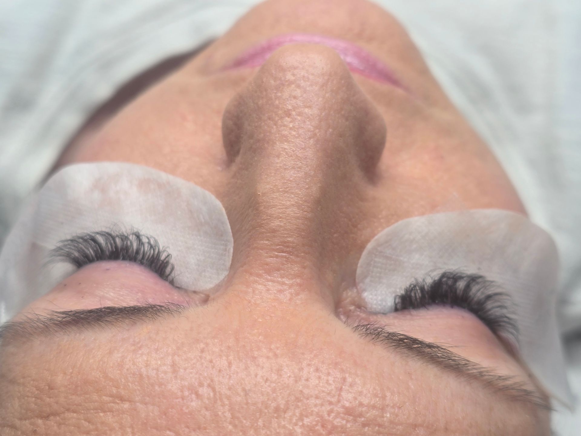 A close up of a woman 's face with paper pads on her eyes.