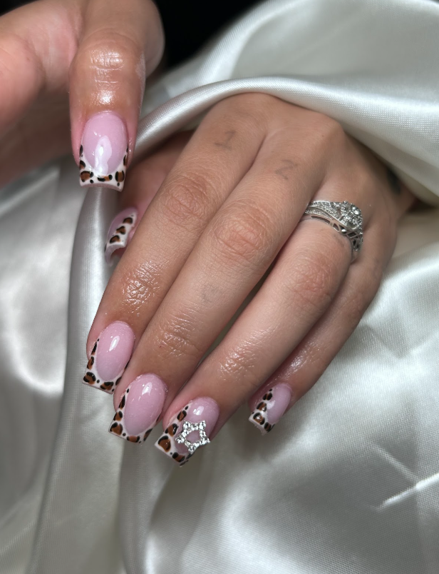 A woman 's hand with a ring and leopard print nails.