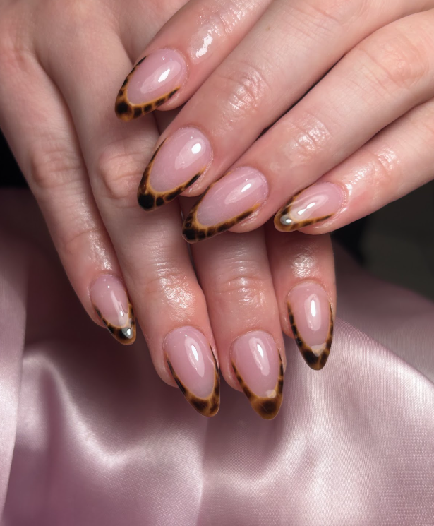 A close up of a woman 's nails with a leopard print design.