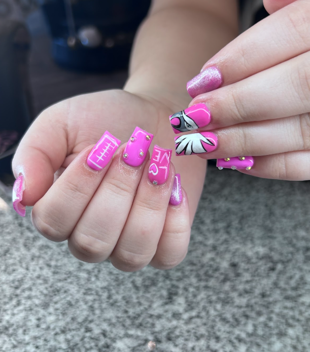 A close up of a woman 's pink nails with a football design.