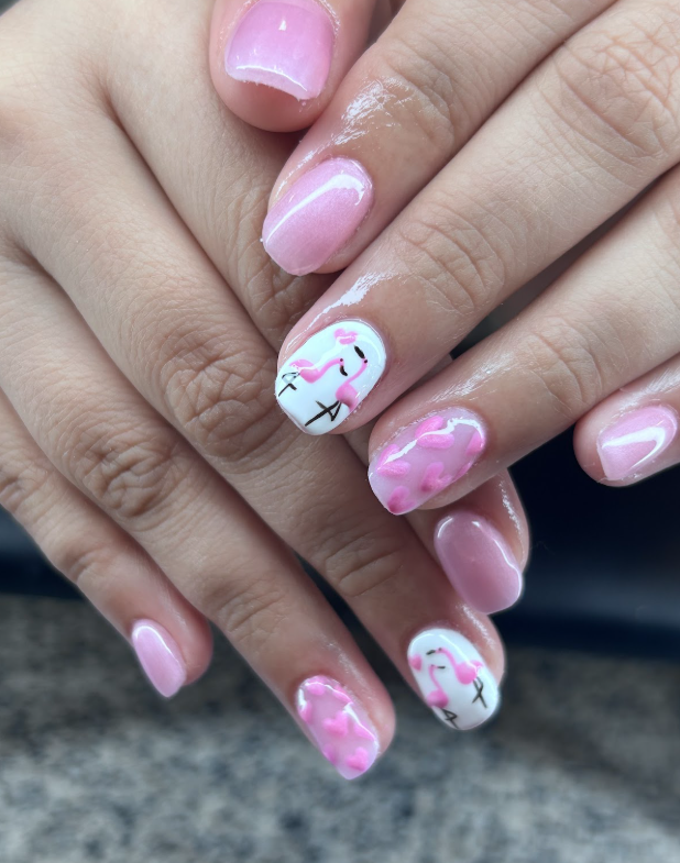 A close up of a woman 's nails with flamingos painted on them.