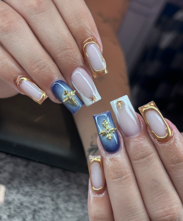A close up of a woman 's nails with blue and gold designs.