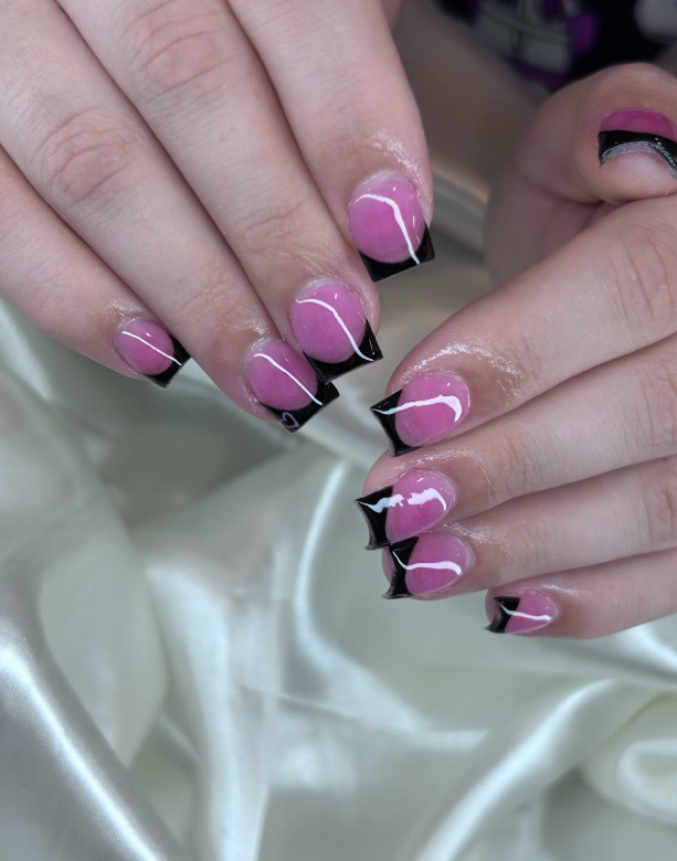 A close up of a woman 's nails with pink and black manicure.