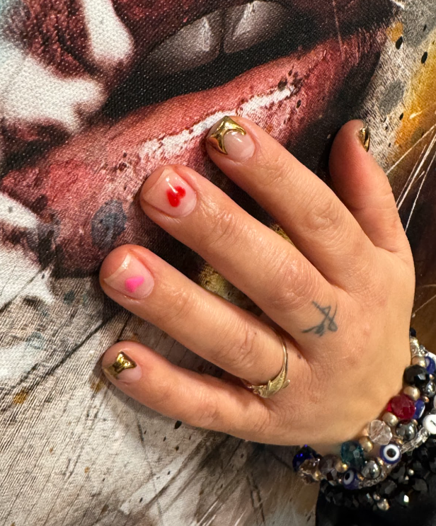 A woman 's hand with a tattoo of a cross on her finger.
