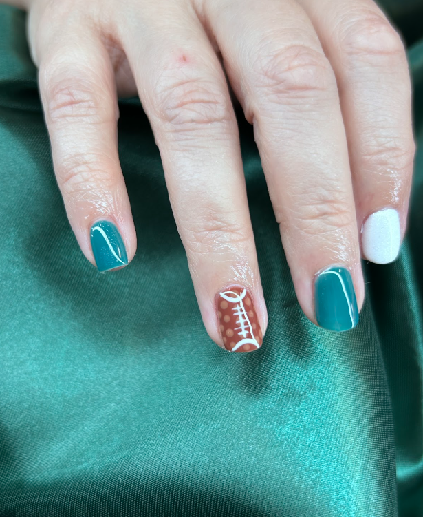 A close up of a person 's nails with a football design on them.