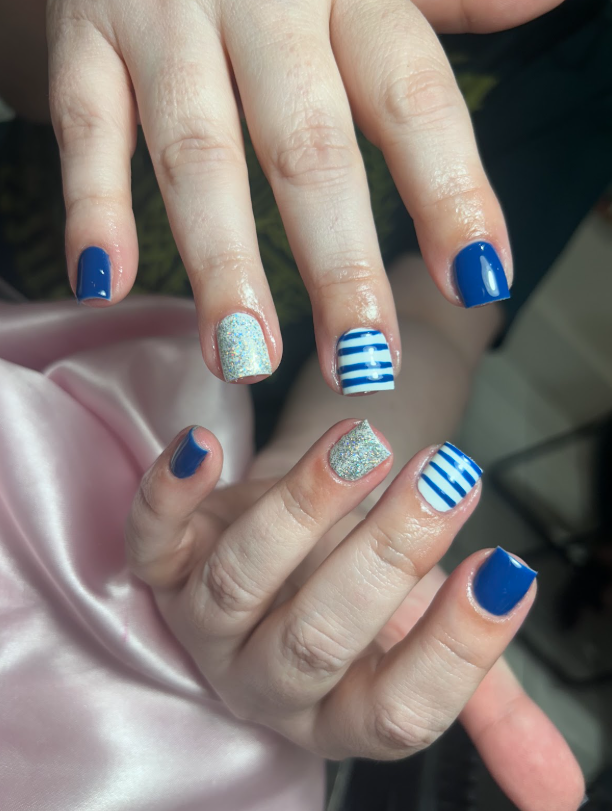 A woman 's nails are painted blue and white with a striped design.
