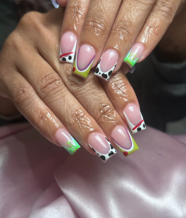 A close up of a woman 's nails with a cow print design.