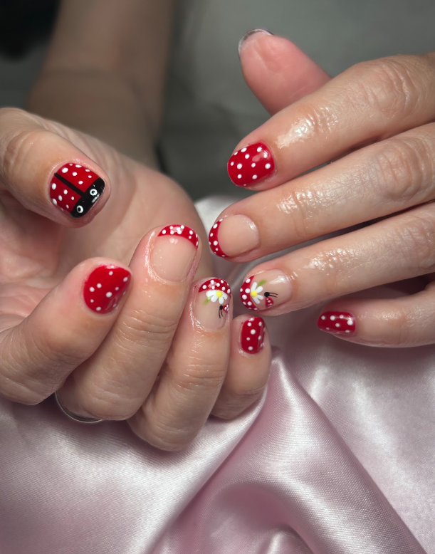 A close up of a person 's nails with a ladybug and polka dots design.