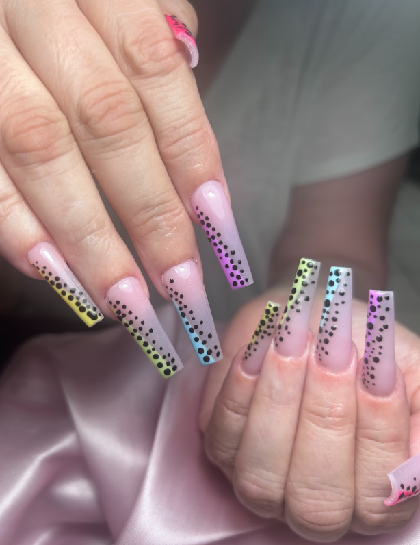 A close up of a woman 's nails with polka dots on them.