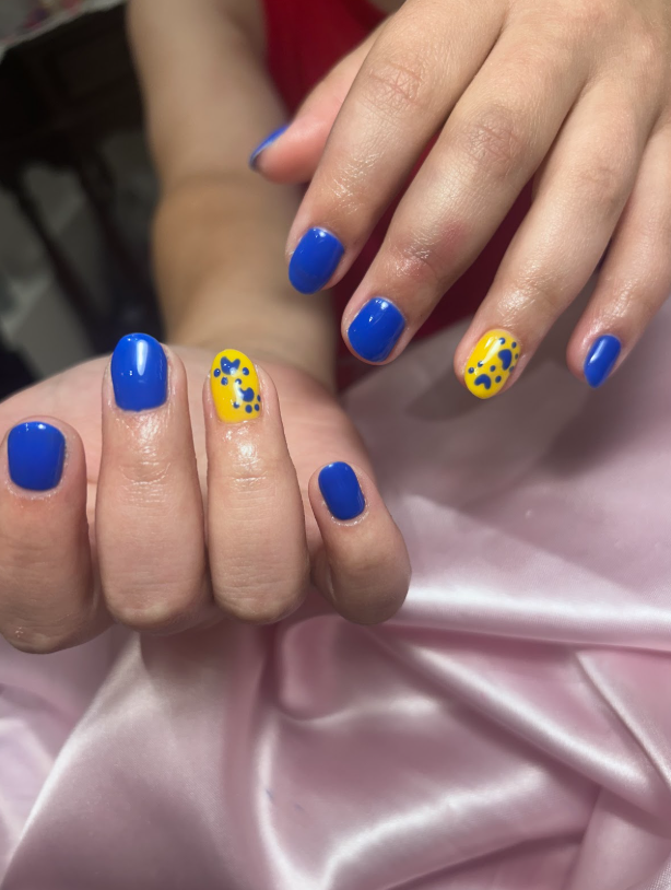A close up of a person 's nails with blue and yellow polish.
