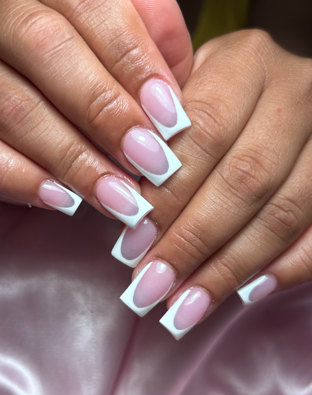 A close up of a woman 's nails with a white French manicure.