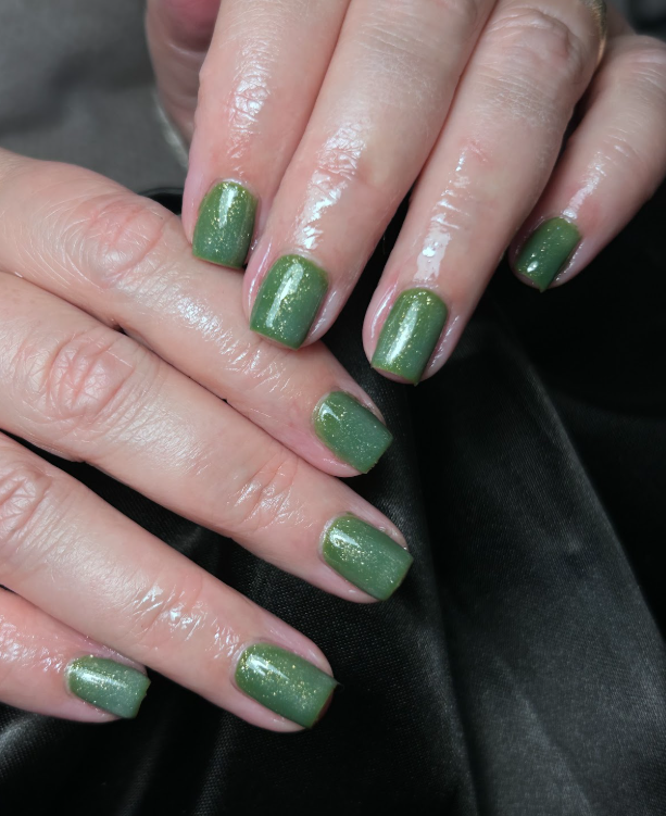A close up of a woman 's nails with green nail polish.